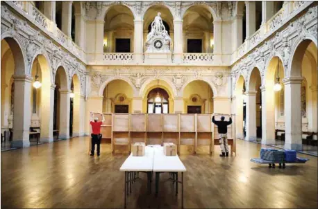  ?? LAURENT CIPRIANI — THE ASSOCIATED PRESS ?? Workers prepare voting booths Saturday at a polling station in Lyon, France. The two-round presidenti­al election will take place today and May 7.