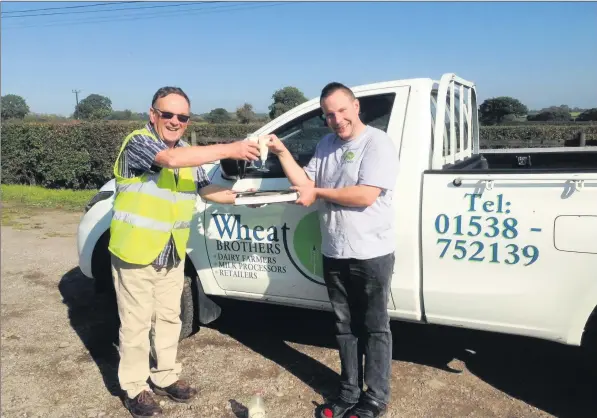  ??  ?? Keith hands his round books to Michael Wheat of Wheat Bros as they wish each other all the best with champagne flutes of milk.