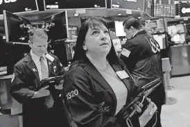  ?? [AP PHOTOS] ?? Trader Phyllis Arena Woods works Wednesday on the floor of the New York Stock Exchange. Stocks and oil prices fell after Washington threatened to expand tariffs on Beijing and China said it would retaliate.