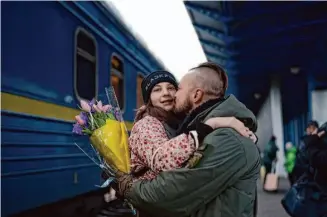  ?? Roman Hrytsyna/Associated Press ?? Soldier Vasyl Khomko hugs his daughter, Yana, after she and her mother arrived at the train station in Kyiv. Khomko’s wife and daughter evacuated to Slovakia after the Russian invasion.