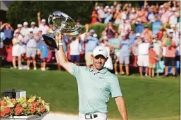  ?? Jason Getz / Associated Press ?? Rory McIlroy celebrates with the trophy after winning the Tour Championsh­ip golf tournament at East Lake Golf Club Sunday in Atlanta.