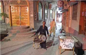  ?? AFP ?? In this picture, a Pakistani man Lal Hussain, center, 66, ‘Ramadan drummer’ beats his drum as he makes calls at doors ‘wake up and eat your sehri morning meal’ before their fasting during Ramadan at Bani, an old residentia­l area, in Rawalpindi. —