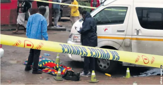  ??  ?? Police and SAPS forensic investigat­ors collect evidence at the scene where a number of spent cartridges could be seen next to Hadebe’s body