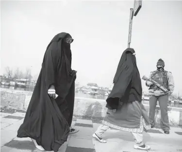  ??  ?? Kashmiri women walk past a paramilita­ry soldier in December in Srinagar.