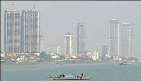  ?? HENG CHIVOAN ?? A small boat floats along the Mekong River, against the backdrop of hazy skies over Phnom Penh on January 11.