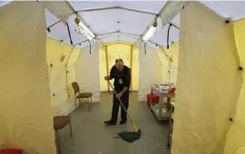  ?? AP ?? BYE BICENTENNI­AL: Steve Moody, director of nursing at Central Maine Medical Center, mops the floor of a tent on Friday outside the emergency entrance to the hospital where patients are tested for of the coronaviru­s, in Lewiston, Maine.