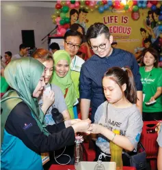  ??  ?? Yii (right, behind girl) looks at the hive of activities at Unimas booth.