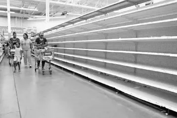  ?? — Reuters photo ?? People walk past empty shelves where bread is normally sold in a Walmart store in advance of Hurricane Irma’s expected arrival in North Miami Beach, Florida, US, September 7.