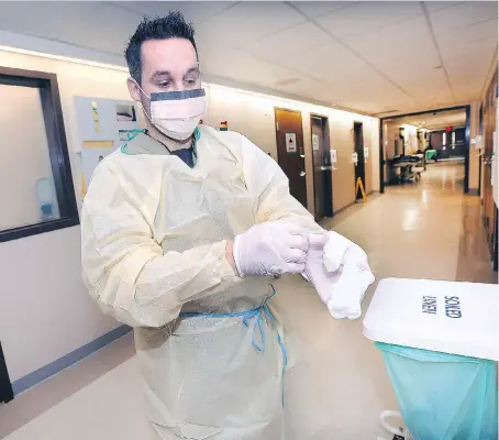  ?? DAN JANISSE ?? Mike Drouillard, a registered nurse at the Windsor Regional Hospital’s Ouellette campus, dons protective garb to guard against exposure to the influenza virus while interactin­g with a patient. So far there have been 25 confirmed flu patients admitted...