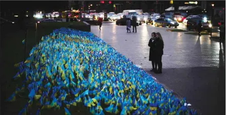  ?? ?? Two women stand next to Ukrainian flags placed in memory of civilians killed during the war at the Independen­ce Square in central Kyiv, Oct. 20, 2022. (AP)