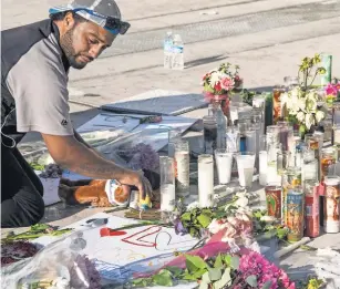  ?? NICK OZA, USA TODAY NETWORK ?? Matthew Edwards, 30, of San Diego places a teddy bear and flowers at a memorial site on the corner of Las Vegas Boulevard and Sahara Avenue.