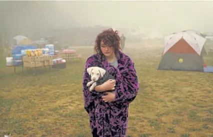  ?? John Locher, The Associated Press ?? Shayanne Summers holds her dog Toph while wrapped in a blanket after several days of staying in a tent at an evacuation center at the Milwaukie- Portland Elks Lodge in Oak Grove, Ore., on Sept. 13, while the area was threatened by the Riverside fire.