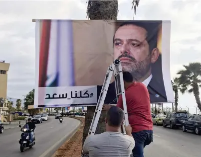  ??  ?? عمال لبنانيون يعلقون ملصقا كبيرا يحمل صورة الحريري وعبارة «كلنا سعد» في أحد شوارع بيروت أمس. (أب)