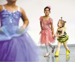  ??  ?? In this company, every dancer on stage is between the age of 3 and 19. Here, Isabel Andalco, 8, holds hands with Londyn Kennedy as they prepare to rehearse.