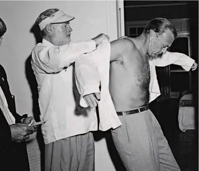  ??  ?? Hemingway ayudando a su amigo Gary Cooper a ponerse la guayabera en su casa de Cuba, en 1956.