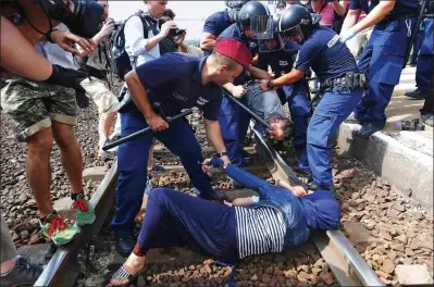  ??  ?? Protest: A couple with a baby struggle with police on the tracks at Bicske station, above and right