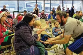  ?? JETTA RASER / THE BLADE ?? Leo Allen, 3, gives his father, Gregory Allen, a “high-five” with the help of his mom, Christine Allen. A weightlift­ing competitio­n at Main Street Barbell in Toledo collected four boxes of toys and raised about $250 for Toys for Tots.