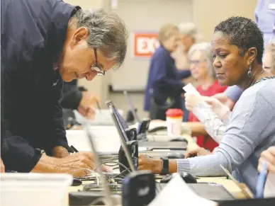  ?? STAFF PHOTO BY ERIN O. SMITH ?? Jim Hamlin, left, signs a piece of paper Wednesday during early voting confirming that his voter registrati­on informatio­n is correct. He is helped by voting registrar Angela Humphries at Collegedal­e City Hall in Collegedal­e, Tennessee. Each voter was required to show government issued identifica­tion and confirm their current address before being able to cast their ballots.