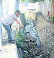  ?? CHRISTOPHE­R SERJU PHOTO BY ?? Damion, a resident of Grants Pen, St Andrew, observes the accumulati­on of garbage in a gully in the northeast St Andrew community.