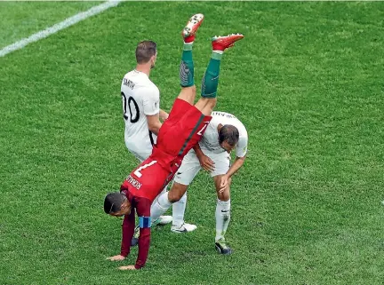  ?? PHOTO: REUTERS ?? Portuguese superstar Cristiano Ronaldo finds himself upended by All Whites defenders Tommy Smith, left, and Andrew Durante in St Petersburg.