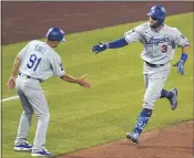  ?? GENE J. PUSKAR — THE ASSOCIATED PRESS ?? The Dodgers’ Chris Taylor slaps hands with third base coach Dino Ebel after hitting a two-run home run against the Pirates on Tuesday night.