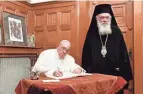  ?? IMAGES VATICAN MEDIA/AFP VIA GETTY ?? Pope Francis, left, signs a document next to Archbishop Ieronymos II, of the Orthodox Church, in Athens, on Saturday.