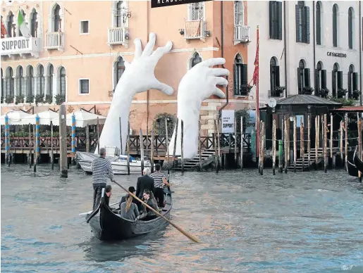  ?? Picture: Neville Green ?? HANDS AND FEATS This artwork in the Grand Canal, Venice, is a comment about the threat of climate change.