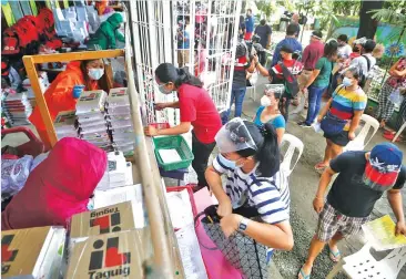  ??  ?? BACK TO SCHOOL — Faculty members at Taguig Integrated High School wear Personal Protective Equipment (PPE) while distributi­ng modules and other school supplies, including anti-COVID-19 kits, to Taguig City’s kindergart­eners. (Ali Vicoy)