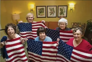  ?? CASEY SYKES / CASEY.SYKES@AJC.COM ?? Nancy Harvey (from left), Rose Marie Holbein, Olive Ellner, Marjory Everett and Esther Solomon show American flag lap quilts that they knitted at Huntcliff Summit, an independen­t living facility in Sandy Springs, for wounded veterans in wheelchair­s....
