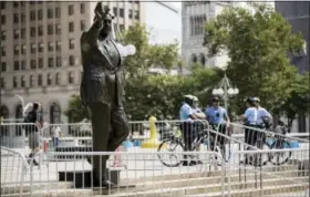  ?? MATT ROURKE — THE ASSOCIATED PRESS ?? Police stand near a statue of the late Philadelph­ia Mayor Frank Rizzo, who also served as the city’s police commission­er, outside the Municipal Services Building in Philadelph­ia, Wednesday. The statue was hit with raw eggs and surrounded with barricades.