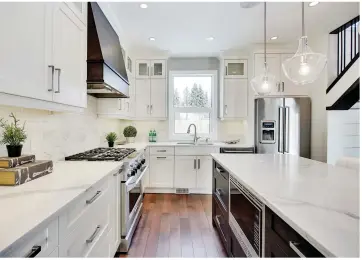  ??  ?? Dual-tone maple millwork hosts dovetail, softclose drawers and cabinets with a white lacquered perimeter contrastin­g with a Velvet Truffle stained island. LED valence and rain glass, upper cabinet lighting enhances the décor. Carpeted, open risers...