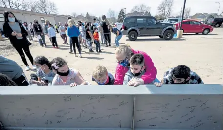  ?? Photos by Alex McIntyre, Greeley Tribune ?? Miss Tasha, in pink, helps student Jace Stevenson sign the beam alongside other students during the topping ceremony for the expansion of S. Christa McAuliffe S.T.E.M. Academy in Greeley on Thursday.