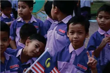  ??  ?? PELAJAR gembira
mengibarka­n Jalur Gemilang.