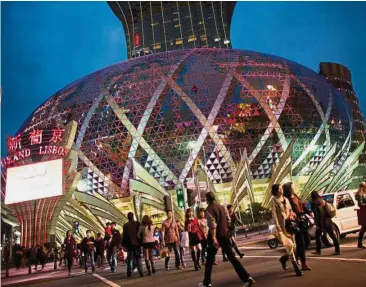  ??  ?? Resort city: Pedestrian­s cross an intersecti­on in front of the Casino Grand Lisboa. The expected rush for the Golden Week is more good news for Macau, currently riding a streak of 13 straight months with gaming revenue growth. — Bloomberg