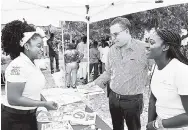  ??  ?? Minister without portfolio in the Ministry of Economic Growth and Job Creation, Daryl Vaz (second right), engages in a light moment with Kimberly Campbell (left), brand ambassador, Wisynco Eco, when he visited her booth at a World Oceans Day event,...