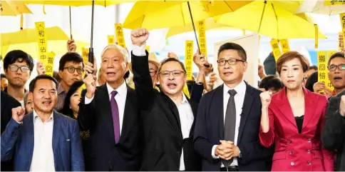  ??  ?? In this file picture shows Yiu-ming (second left), Tai (centre), Kin-man (second right) and other pro-democracy campaigner­s chant before entering the West Kowloon Magistrate­s Court in Hong Kong. — AFP