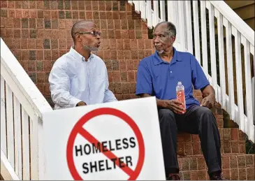  ?? HYOSUB SHIN/AJC 2016 ?? In 2016, Devon Holloway (left) and former state Rep. Douglas Dean chat outside Holloway’s home in the Pittsburgh neighborho­od of Atlanta. Holloway has been largely heartened by what he has witnessed since. But issues remain such as dumping, apathetic residents and LLCS that buy houses and leave them vacant till the owners can score big.