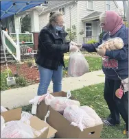  ?? LYRIC AQUINO — THE MORNING JOURNAL ?? Jessica Santiago, left, gives bread and bagels to a community member for free on Oct. 24.