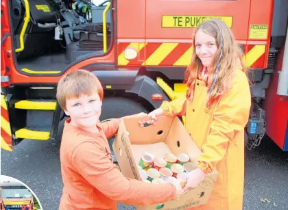  ?? Photos / Stuart Whitaker ?? Colin Neal hands over a box of cans to Jodi Deacon on the Te Puke Emergency Services Food drive.