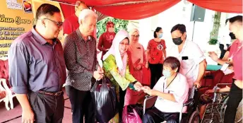  ?? ?? Fatimah presents an angpow (cash aid) and food to a recipient, witnessed by Pui (second left) and others.