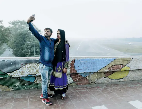  ??  ?? PICTURE IMPERFECT: A couple takes a selfie from a flyover above the Sarfdajung airport. Delhi residents have been posting “smog selfies” to social media to show how bad the air quality has become.