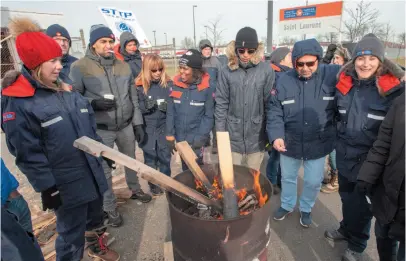  ?? CP FILE PHOTO ?? Striking Canada Post workers stay warm around the fire as they walk the picket line in front of the Saint-Laurent sorting facility in Montreal on Nov. 15. Rotating postal strikes has caused a backlog of deliveries.