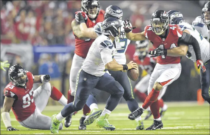  ?? HYOSUB SHIN / HSHIN@AJC.COM ?? Seahawks quarterbac­k Russell Wilson has to hustle to avoid being tackled by Falcons outside linebacker Vic Beasley (44) in the second half.