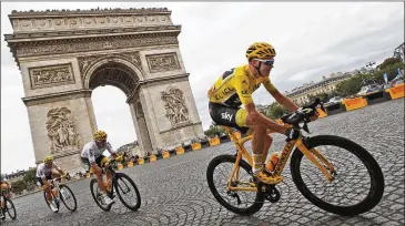  ?? CHRISTOPHE ENA / AP ?? Chris Froome, wearing the overall leader’s yellow jersey, passes the Arc de Triomphe on Sunday during the 21st and final stage of the Tour de France. Froome won his third straight title and fourth overall.