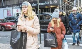  ?? STEPHANIE KEITH/GETTY ?? People carry shopping bags Dec. 20 in New York City. A poll shows that while Americans are mostly grateful around the holidays, stress and sadness also accompany festivitie­s.