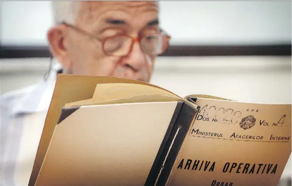  ?? THE ASSOCIATED PRESS ?? A man who refused to be identified by name reads a communist-era secret police file in Bucharest, Romania. The country’s secret police kept a large file on Katherine Verdery, who recounts in her memoir that she was doing research on Romanian village life in the 1970s and ’80s.