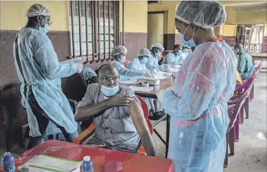  ?? Photo: Carol Valade/afp & John Wessels/afp ?? Prevention: A staff member at N’zerekore’s hospital (above) gets his ebola vaccinatio­n in February. The first cases in the latest emergence of Ebola were at the hospital in late January. Guinea shares a border (below right) with Sierra Leone, Liberia, Guinea Bissau, Mali, Senegal and Côte d’ivoire. N’zerekore is at the intersecti­on of roads from Liberia and Côte d’ivoire as well as from Kankan and Macenta in Guinea. Health workers (below left) bury a coffin of an Ebola victim in May 2019.