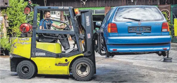  ?? FOTO: CHRISTOPH SCHMIDT/DPA ?? Wolfgang Richard befördert einen alten VW-Polo mit seinem Gabelstapl­er: Früher konnte man mit Schrott Geld verdienen, jetzt kämpfen viele Inhaber um ihre Existenz.