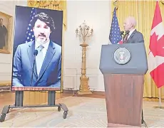  ?? — AFP photo ?? Biden (right) and Trudeau (on screen) speaks to the media after holding a virtual bilateral meeting in the East Room of the White House in Washington, DC.