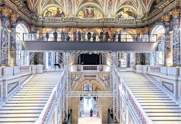  ??  ?? Visitors stand on a suspended bridge, 12m above ground, to take a closer look to paintings by Austrian painter Gustav Klimt at the Kunsthisto­risches Museum in Vienna.